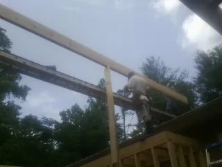 Carpenter setting a ridge beam over a new addition frame — Ice Dam Removal by Roofing Brothers in Waban