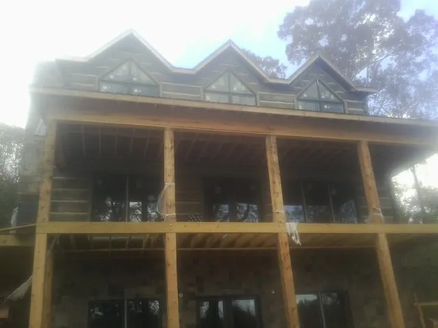 Dormers and porch framing on a large log home under construction — Roof Coating work by our crew in Waban