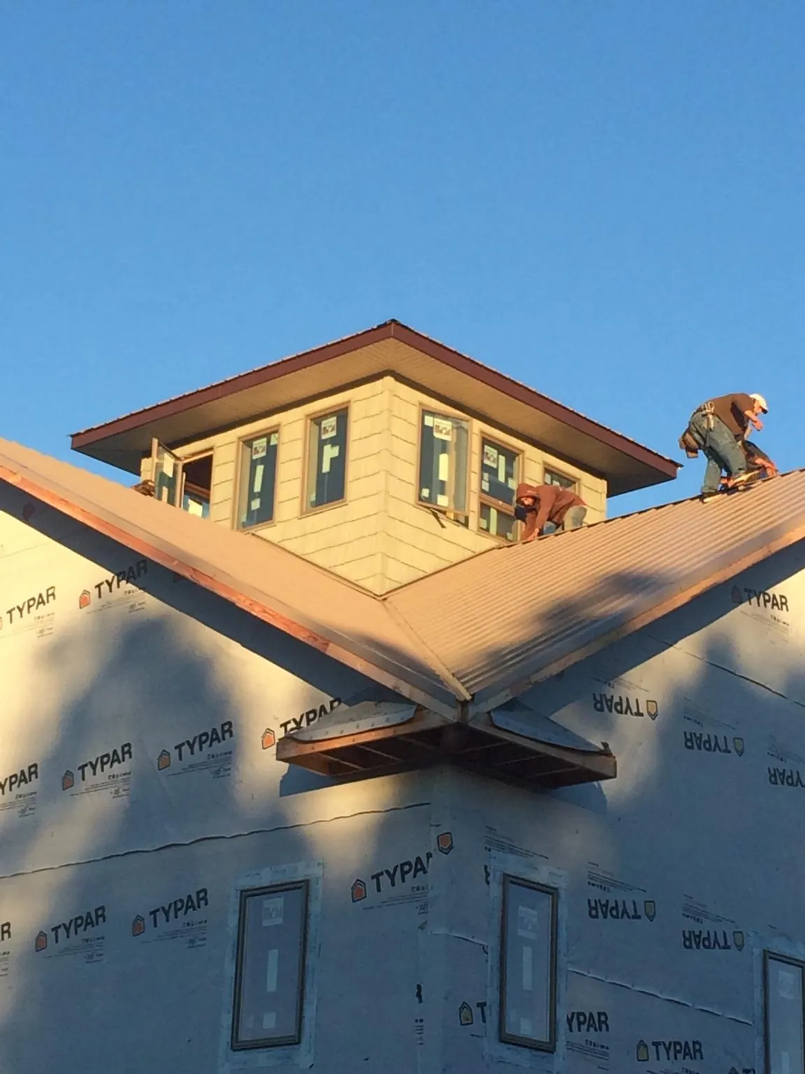 Roofers working around a rooftop cupola on a new metal roof at sunset — Roof Waterproofing in Waban by Roofing Brothers